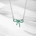 Gros plan d'un pendentif nœud argenté avec zircon vert sur une chaîne à maillons fins - Argent / Zirconia Vert