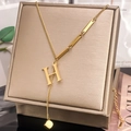 Detail of gold-plated Y-necklace featuring an H letter pendant and sleek metal bar - Letter H