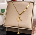Detailed close-up of gold V-letter lariat necklace with square charm on silk - Letter N