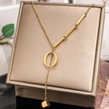 Detail of gold letter O necklace with geometric bars and cube pendant on leather stand - Letter O