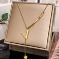 Detailed close-up of golden V-letter pendant necklace with rectangular bar tassels - Letter V