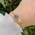 Detail of 18K gold-plated bracelet with blue flower charm and pave heart on wrist - Blue