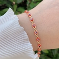 Detail of gold evil eye bracelet with red beads worn on wrist against a soft background - Bracelet / Red