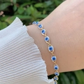 Close-up of a 18K gold plated evil eye bracelet worn on a wrist with nature backdrop - Bracelet / Blue