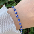Detail of 18K gold plated Evil Eye bracelet with blue charms on a female wrist - Bracelet / Blue