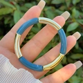 Close-up of blue and gold tubular resin bead elastic bracelet worn on a female wrist - Blue and Gold (5)