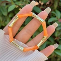 Primo piano del bracciale in resina arancione traslucida e metallo dorato indossato al polso - Arancione (Giunto Oro)