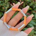 Dettaglio del bracciale a maglie di bambù in resina e argento regolabile indossato al polso - Arancione Brillante (Giunto Argento)