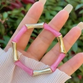 Dettaglio del bracciale a perline con segmenti di bambù in resina rosa e oro al polso - Rosa (Giunto Oro)