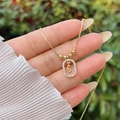 Macro detail of a 18K gold-plated oval pendant with letter G and sparkling zircons - Gold G