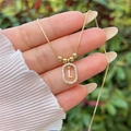 Detail of 18K gold plated necklace featuring an oval pendant with a sparkling letter L - Gold L