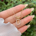 Close-up of gold plated necklace with iced out zircon oval V letter pendant held in hand - Gold V