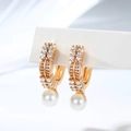 Macro detail of gold-plated hoop earrings with pavé zircon stones and a hanging white pearl - Double Row Prong Setting (EH871)
