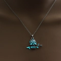 Macro view of gothic skull necklace pendant with glowing blue eyes and a rose stem - Blue-Green Luminous