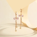 Macro detail of gold-plated bow earrings featuring pink zircon drops and long tassel chains - Gold Pink Zirconia
