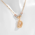 Macro detail of textured gold D letter pendant with colorful beads on a delicate chain - Letter D