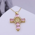 Makroaufnahme von Kreuzanhänger mit rosa Zirkonia und zentralem religiösem Ikonen-Detail - Rosa