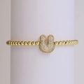 Detalle de pulsera de cuentas doradas con un colgante en forma de U pavonado con circonitas - Letra U
