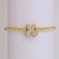 Primer plano de pulsera dorada de cuentas con colgante de flor y circonitas blancas - Letra X