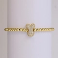 Detalle de una pulsera de cuentas doradas con un colgante de lazo pavimentado con circonitas - Letra Y
