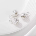 Drie holle zilveren tijgerkop belletjes voor DIY sieraden op een witte keramische tray - 10mm / Zilver