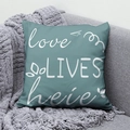 Detail view of teal pillow with white Love Lives Here text on a grey sofa - 45x45 / Love Lives Here Teal Design (DRD291-11)