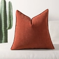 Terracotta chenille kussenhoes met visgraattextuur op een witte bank met plant - Roestoranje