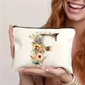 Smiling woman holding a cream canvas makeup bag featuring a floral letter F pattern - Letter F (TSND27-6) / 21.5x15cm