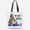 White canvas tote bag featuring 'Booked and Busy' cartoon illustration and black straps - Tfbd26-15; 33*39cm; 12 Oz Polyester-cotton Canvas (single-sided Printed)