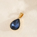 Macro-opname van blauwe druppelvormige hanger met gepolijste goudkleurige zetting - Saffierblauw