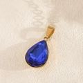 Macro-opname van de vergulde druppelvormige hanger met blauwe kristallen detail - Marineblauw