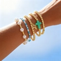Chic 18K gold plated bead bracelet set with cross pendants on a sunny sky background - Stacked Set