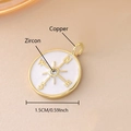 Macro detail of a 1.5cm gold-plated copper compass pendant with white enamel and zircon - Gold Plated Compass (NAK11-5)