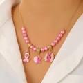 Gros plan de pendentifs en émail rose sur un collier en perles dorées porté par un mannequin - Collier de Charité en Perles Roses (5205)