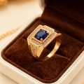 Makroaufnahme eines Luxusherrenrings mit tiefblauem Stein in einer braunen Samtbox - US 7 / Gold Quadratischer Blauer Edelstein