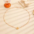 Nahaufnahme der goldenen Taillenkette mit Plumeria-Blütenanhänger bei sanftem Licht - 55 KC-Gold Strukturierte Blume (K-881)