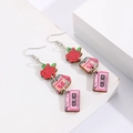 Détail de boucles d'oreilles en bois avec cœur rose et cassette LOVE SONGS sur présentoir - Rose et Calendrier (12043)