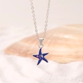 Exquisite silver starfish necklace with sparkling blue pendant over white sand beach scenery - 14K White Gold Plated Alloy