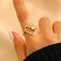 Irregular hollow heart ring in golden finish with sparkling zircon stone on index finger - Heart Hollow Round Zircon Style (DZ-062)