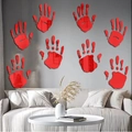 Detail view of 8 red acrylic bloody handprint mirror stickers on a living room wall - Red