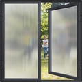 Vertical fluted glass film on black frame showing privacy frosting and soft outdoor view - Vertical Ribbed / Small Size (One Roll)