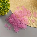 Vista dettagliata di adesivi murali a stella 3D rosa sparsi su un tavolo con un cappello - Rosa