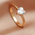 Macro detail of a sparkling heart-shaped zircon ring on a soft pink silk background - Gold White Zirconia