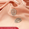 Macro shot of silver skull earrings with glitter texture on pink satin background - Skull Style