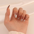 Macro view of a minimalist silver hollow water-drop fingertip ring on white satin fabric - Open Nail Ring (M-383) / White Gold