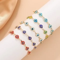 Golden Evil Eye charm bracelets in red, blue, and green hanging on a display stand - Five Style 11069