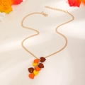 Dettaglio di una collana a foglia d'acero dorata con pendenti in resina rossa e gialla - Collana Foglia di Acero (02 KC Gold)