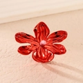 Macro shot of a red metal flower earring with textured petals and purple center bead - Red Ring