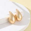 Detailed view of glossy gold teardrop stud earrings on a geometric display stand - Gold