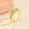 Detail of gold snake-shaped ring with pavé zircons on textured beige sand background - 14K Gold